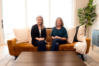 Real estate agents Lauren and Jennifer of Haug & Co. seated on couch during team brand shoot