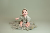 Baby girl wearing a green romper during her milestone session at Jennifer Brandes Photography studio in New Ulm, Minnesota.