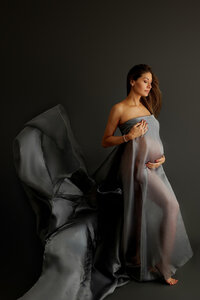 Liberte wrapped in flowing fabric during fine art maternity portrait session in North Hollywood, moody setting
