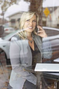 Business owner working on a phone and laptop at a coffee shop during a Ventura County brand photography session.