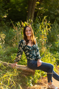 A Brookfield Central High School senior perches on the end of a log in Waukesha's Minooka Park while her portrait is taken.