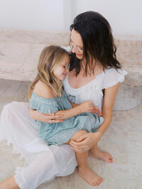 Mom cuddling her daughter on the floor during their portrait session in Seattle
