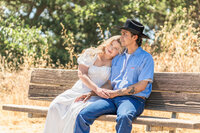 Couple sitting together on a bench during a summer engagement photo session in Orange County.