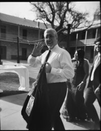 A wedding guest waving to the camera as he walks to the outdoor ceremony in San Antonio shot on black and white 120 film.