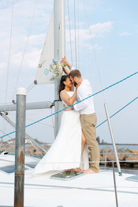 An elopement couple shares a kiss on a sailboat on Lake Superior