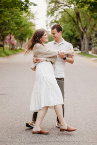 A happy couple dances in the streets during a sweet session with a Duluth wedding photographer, S Jacobson Photography.