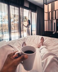 Traveler enjoying a cozy morning with coffee in bed, capturing relaxation and slow travel vibes.