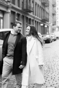Couple smiles while holding hands as they walk through Soho NYC streets