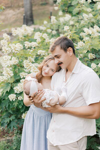 new parents in front of hydrangeas with newborn in peoria il newborn photos