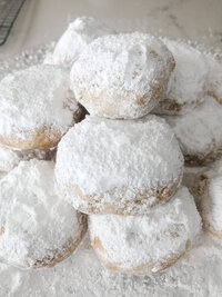 greek kourabiedes cookies stacked on top of each other on a plate with icing sugar.