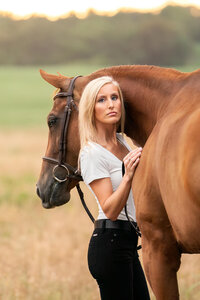 blonde equestrian hugging her chestnut American Quarter Horse mare in a field with golden light behind them