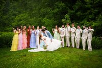 Bride and groom sharing a joyful moment with their bridal party in colorful dresses