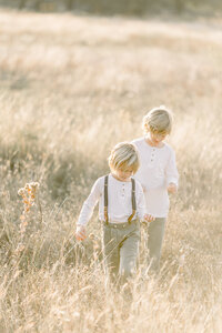 Two young brothers walking though a local DFW parks grassy field.