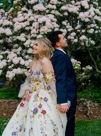 bride and groom looking in distance in front of pink flowers