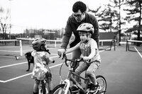 A dad helps teach his son how to ride a bike
