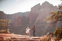 Couple dancing playfully together on Sedona's red rocks during their elopement
