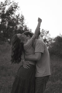 A man and woman spin around romantically spin around in the snowy forest