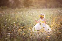 Young girl in a floral crown and full tulle dress moves through tall wildflowers while chasing a butterfly during a Midwest signature fairy adventure session. (Photographed by Nature's Child Photography)