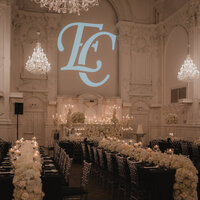 Salle de réception élégante à la Maison Principale avec arrangement floral blanc, lustres de cristal et initiales en lettres géantes