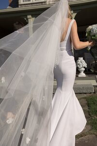 Veil blows in wind as bride and groom walk down aisle.