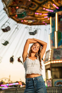 Senior portrait at the Greater Gulf State Fair in Mobile, Alabama — waist-up with hands above
her head in front of the swing ride.