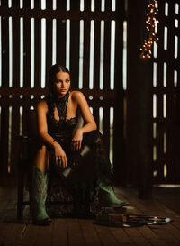 Senior portrait at Triple T Farms in Fruitdale, Alabama — holding a vinyl record with teal cowboy
boots on a stack of books.