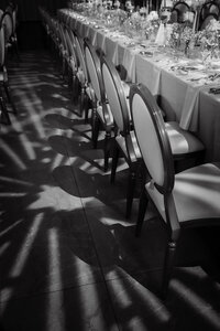 Lumière naturelle projetant des ombres graphiques de chaises élégantes alignées, à côté d’une table dressée, dans l’ambiance feutrée et poétique du Théâtre Saint-James à Montréal.