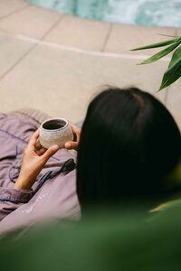 Overhead of a guest holding tea beside the pool