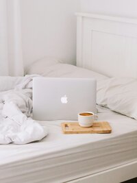 Laptop computer with a cup of coffee and a blanket sitting on chair