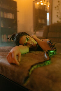 Moody conceptual portrait featuring an artist posed with a snake.