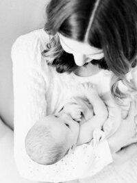 Black and white overhead portrait of a mother looking down lovingly at her newborn baby during an in-home newborn session.