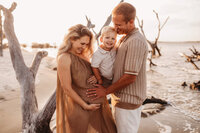 Folly Beach Maternity Photographer -- Pregnant woman poses for Maternity Photos at the Lighthouse Inlet Heritage Preserve on Folly Beach with iconic views of the Morris Island Lighthouse in the distance.