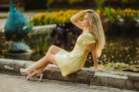 A girl from Waukesha North High School sits on a concrete wall along a pond in Eagle's Paradise Springs for her senior portraits.