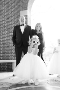 Small flower girl walks down the aisle in sunglasses