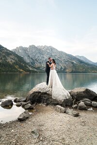 Elopement couple stands on rock at Jenny lake in Grand Teton National Park