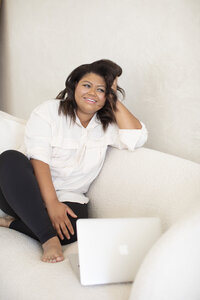 girl sitting white couch laptop smiling