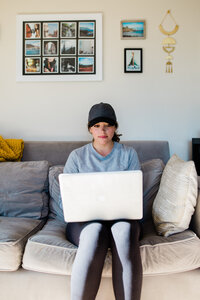 A photographer sitting on the couch with her laptop.