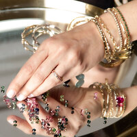 Branding photography Three Stories Jewelry closeup of hand touching various beads on mirror tray