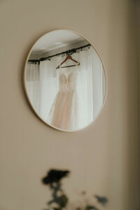 White wedding dress hanging on a round mirror