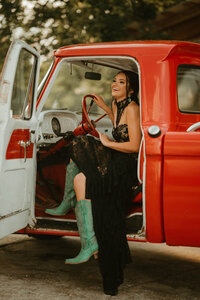Senior portrait at Triple T Farms in Fruitdale, Alabama — laughing in the driver’s seat of a
classic red truck, wearing teal cowboy boots.