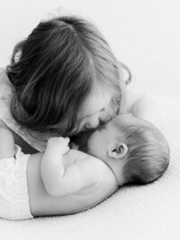 Big sister kissing newborn baby sister during a Portland newborn photographer session.