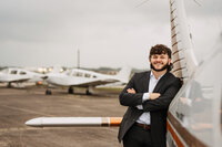 Senior portrait by a small airplane near the Mobile International Airport.