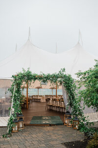 A sailcloth wedding tent set up at Spring Lake Golf Club, with an ivy-covered entrance and wooden lanterns lining the pathway