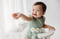 Charleston Cake Smash Photographer - Baby smiles at the camera during Milestone Portrait Session at Holy City Babies in Charleston, SC.