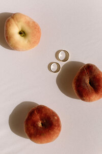 Close-up of gold wedding bands with peaches for a summer garden wedding inspiration.