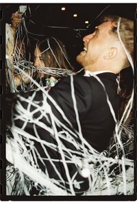 A couple caught in white streamers during their wedding day send off shot on film with flash.