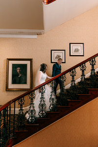 newlyweds walking up stairs together at Exeter rougemont captured by a colourful candid wedding photographer