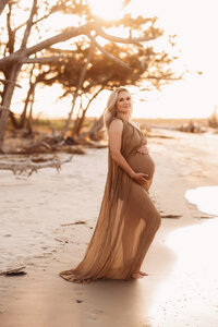 Folly Beach Maternity Photographer -- Pregnant woman poses for Maternity Photos at the Lighthouse Inlet Heritage Preserve on Folly Beach with iconic views of the Morris Island Lighthouse in the distance.