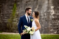 St. Augustine wedding capturing a newlywed couple holding hands and gazing at each other, the stone walls of Castillo de San Marcos creating a historic backdrop. (Photographed by Nature's Child Photography)