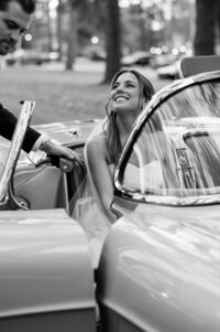 Groom helps bride out of the convertible